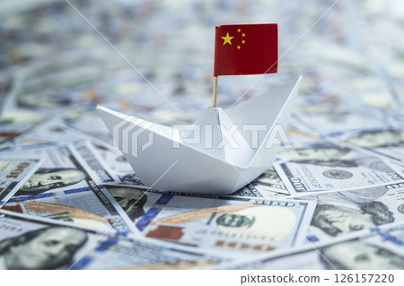 Paper boat with the Chinese flag sailing on dollar banknotes. Concept of economy, financial or government Paper boat with the Chinese flag sailing on dollar banknotes. Concept of economy, financial or government 126157220
