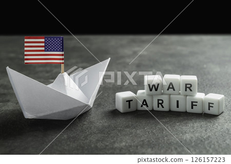 Paper boat with the USA flag and cubes with the text of war tariff on a black background. Concept of the United States of America versus China trade war disputes or economic conflict Paper boat with the USA flag and cubes with the text of war tariff on a black background. Concept of the United States of America versus China trade war disputes or economic conflict 126157223