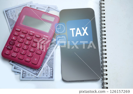 Pink calculator and a pile of 100 dollar banknotes with a notebook and cellphone with tax text on a white background. Mockup or Copy space. Concept of finance and taxation Pink calculator and a pile of 100 dollar banknotes with a notebook and cellphone with tax text on a white background. Mockup or Copy space. Concept of finance and taxation 126157269