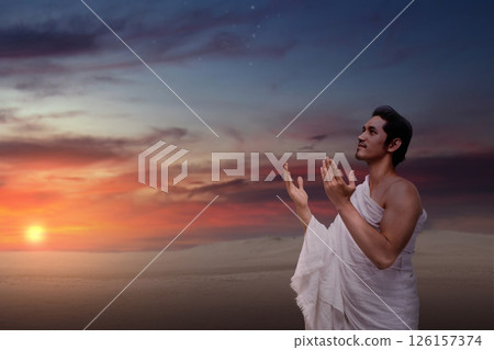 Indonesian southeast asian muslim man wearing white traditional clothes or ihram raises his hand and prays on the hajj. Concept of hajj or umrah Indonesian southeast asian muslim man wearing white traditional clothes or ihram raises his hand and prays on the hajj. Concept of hajj or umrah 126157374
