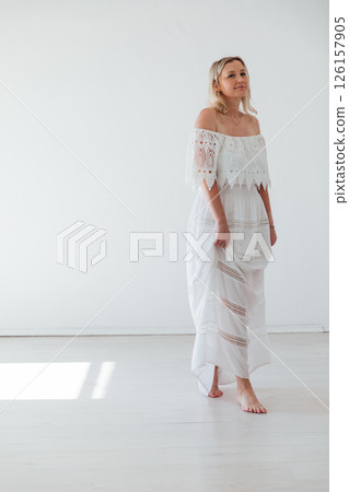 Beautiful blonde woman in summer dress smiling in bright room Beautiful blonde woman in summer dress smiling in bright room 126157905