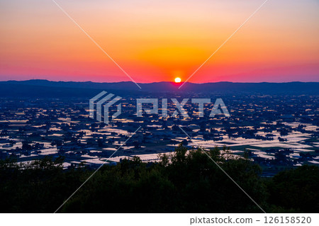 [A magnificent view in early summer] Sunset in the Tonami Plain and scattered villages in early summer and reflections in the rice fields [Toyama Prefecture] 126158520