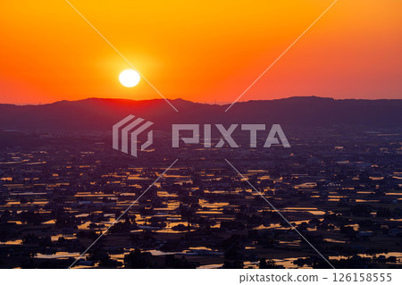[A magnificent view in early summer] Sunset in the Tonami Plain and scattered villages in early summer and reflections in the rice fields [Toyama Prefecture] 126158555