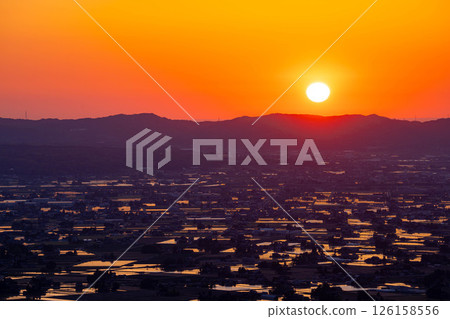 [A magnificent view in early summer] Sunset in the Tonami Plain and scattered villages in early summer and reflections in the rice fields [Toyama Prefecture] 126158556