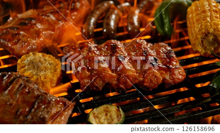 Close-up of Tasty Pork Ribs on Barbeque Grill with Roaring Flames 126158696