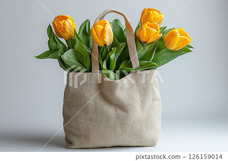 Reusable shopping bag made of fabric with a bouquet of yellow tulips on a white background. 126159014