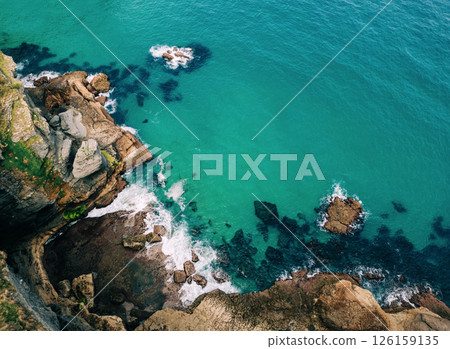 Top down view of rugged coastal cliffs and turquoise waters 126159135