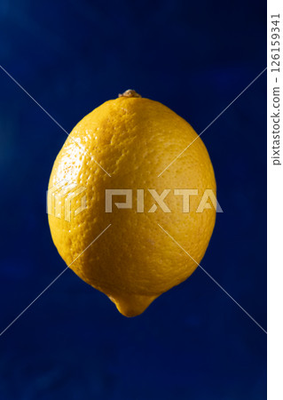 Studio photo of a ripe yellow lemon on a blue background. Levetation. 126159341
