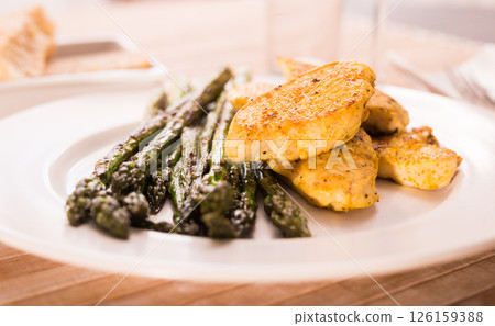 Cooked dish. Chicken nuggets with green asparagus on plate 126159388