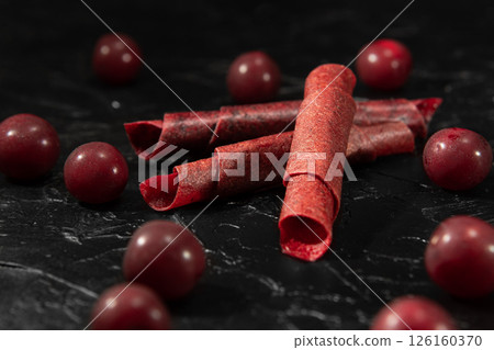 Fruit peel of cherry in rolls. Pastila. Background for text and articles about eating healthy. Raw food diet, vegan sweetness, dessert without sugar and flour. Cherry background. 126160370