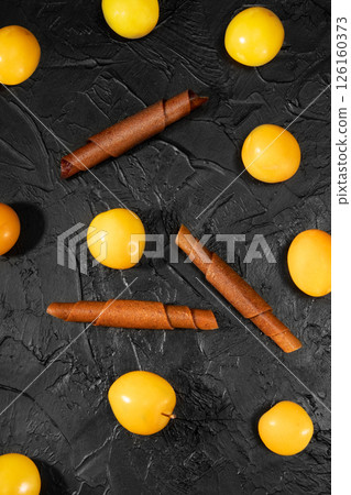 Fruit peel from cherry plum in rolls. Pastille. Background for text and articles about healthy eating. Breakfast in hand. Raw food diet, vegan sweetness, dessert without sugar and flour. 126160373