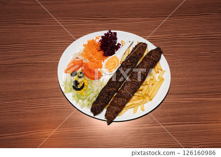 Turkish kebab plate with fries, vegetables and sausages. Delicious freshly prepared meal, perfect for menus, restaurants, or food delivery concepts. 126160986