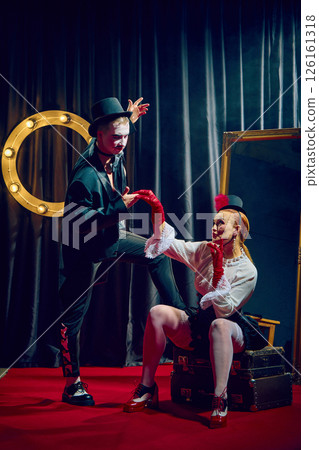 Elegant cabaret duo in top hats posing in smoke and spotlight on stage with romantic dramatic flair. 126161318