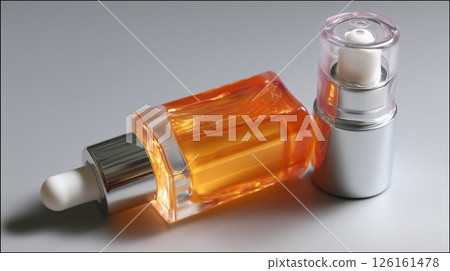 Serum bottles on a reflective surface showcasing orange and clear liquid for skincare routines 126161478