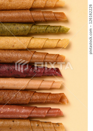 Paste. Pattern of various pastila fruit leather rolls with fruit on a beige background. Vertical. 126162226
