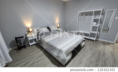 Modern bedroom interior featuring minimalist neutral decor, clean lines, wooden flooring, and soft bedding. The room exudes a cozy, inviting atmosphere for relaxation and comfort Modern bedroom interior featuring minimalist neutral decor, clean lines, wooden flooring, and soft bedding. The room exudes a cozy, inviting atmosphere for relaxation and comfort 126162381