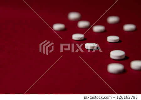 White pills on red background. White pills on red background. 126162783