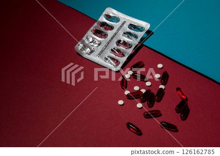 A used plate of pills on a red blue background. Scattered tablets. A used plate of pills on a red blue background. Scattered tablets. 126162785