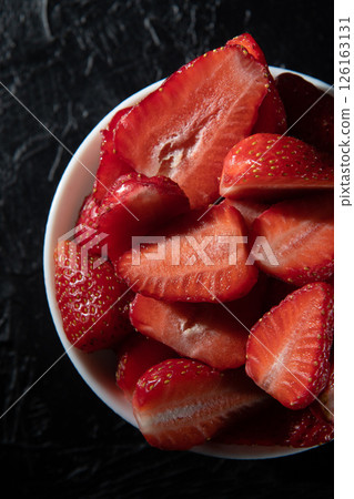 Red ripe strawberries in a saucer on a black background close-up. Red ripe strawberries in a saucer on a black background close-up. 126163131