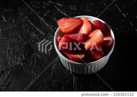Delicious strawberries in a saucer on a black background. Delicious strawberries in a saucer on a black background. 126163132