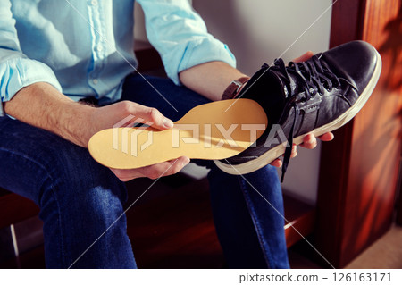 Elegant man holds a leather shoe and puts insole in it 126163171