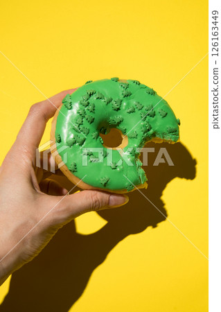 Green donut in hand Photo vertical in studio 126163449