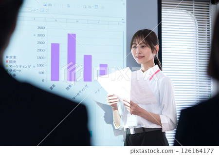 Young woman in casual clothes giving a presentation in front of a screen 126164177