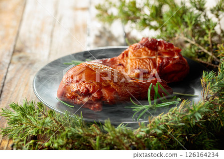 Smoked chicken drumsticks and juniper branches on a wooden table. 126164234