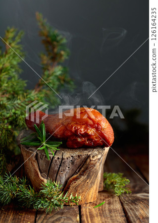 Smoked chicken drumstick and juniper branches on a wooden table. Smoked chicken drumstick and juniper branches on a wooden table. 126164235
