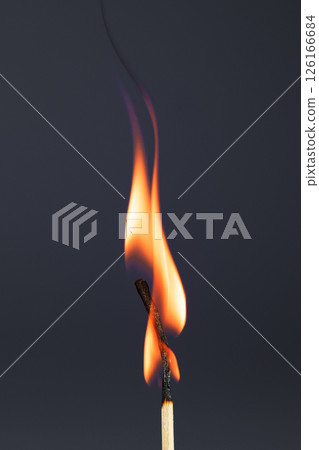 Burning match on a gray background. A wave of yellow flames. Burning match on a gray background. A wave of yellow flames. 126166684