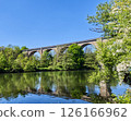Old railway viaduct reflecting in the river on sunny spring day 126166962