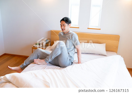 Japanese man sitting on bed and relaxing Japanese man sitting on bed and relaxing 126167315