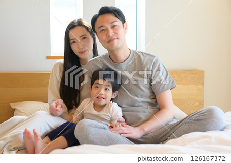 A close family relaxing in bed and sharing a smile in the morning A close family relaxing in bed and sharing a smile in the morning 126167372