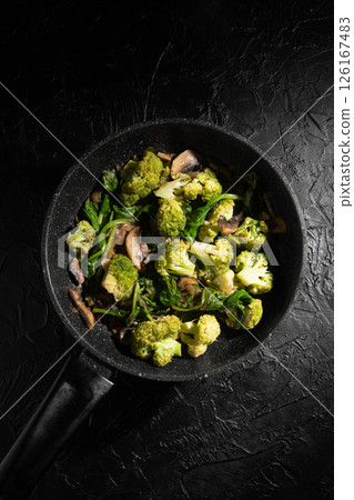 Dish Fried vegetables with mushrooms in a non-stick pan. Broccoli, spinach, onion in olive oil. Cooking healthy food. Dish Fried vegetables with mushrooms in a non-stick pan. Broccoli, spinach, onion in olive oil. Cooking healthy food. 126167483