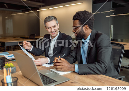 Two businessmen sitting in the office at the laptop and working on the project 126168009