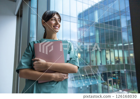 Smiling dark-haired female doctor in lab coat with a medical history in hands 126168030