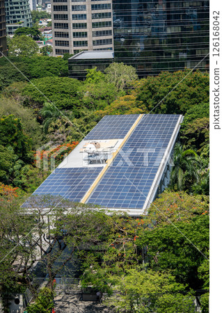 Building rooftop with solar panels energy efficiency surrounded by trees. Ecological architecture Building rooftop with solar panels energy efficiency surrounded by trees. Ecological architecture 126168042