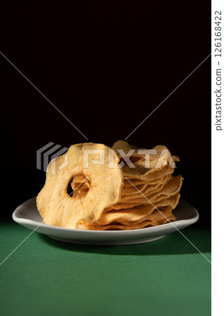 Dried apples on a white plate. Studio photo on a dark background. 126168422