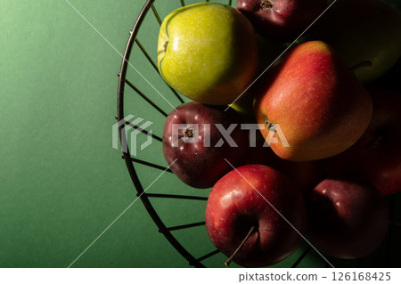 Basket with juicy fresh apples on a dark green background. Top view, studio photo. 126168425