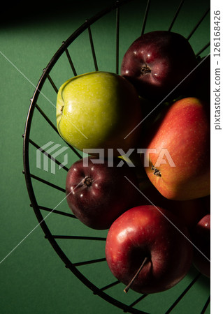 Basket with juicy fresh apples on a dark green background. Top view, studio photo. 126168426
