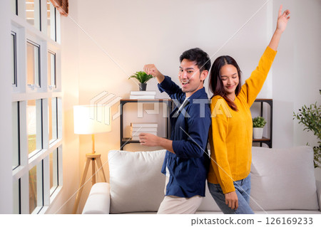 Young asian couple dancing playful together in cozy living room at home, smile and enjoy. 126169233