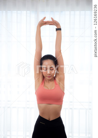 Beautiful young asian woman standing workout with warmup and stretch muscle arm and hands. 126169236