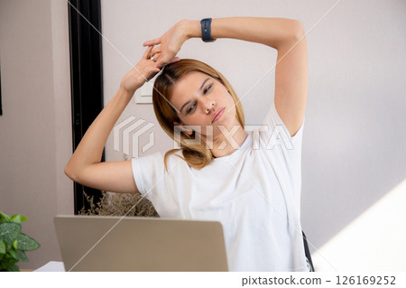 Portrait young caucasian businesswoman taking a break after overworked with stretching arm and hand. 126169252
