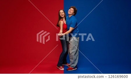 Happy couple, man and woman laughing, hugging in dynamic pose on red blue background, showing joy, love and connection. 126169600