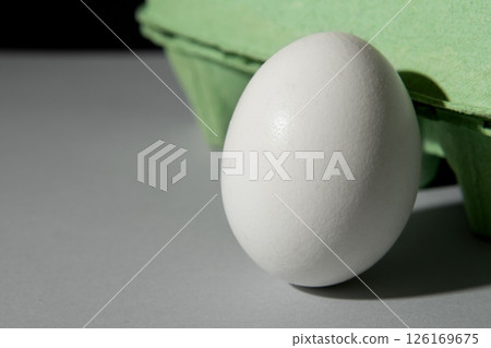 Fresh white egg on the background of a green tray on a gray table. 126169675