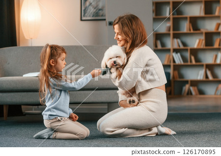 Woman is giving pet for the girl. Present for the daughter. Mother is at home with maltese dog 126170895