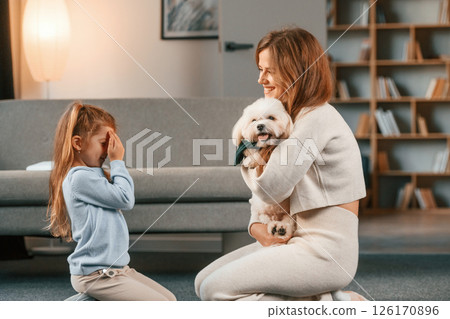 Woman is giving pet for the girl. Present for the daughter. Mother is at home with maltese dog 126170896