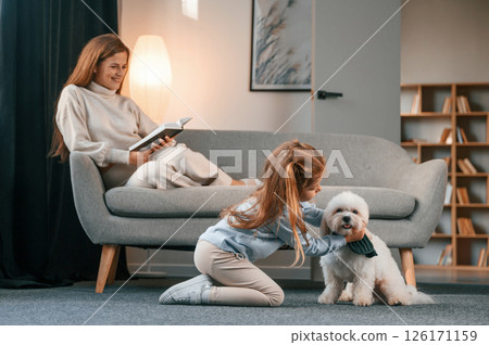 Mother with daughter is at home with maltese dog 126171159