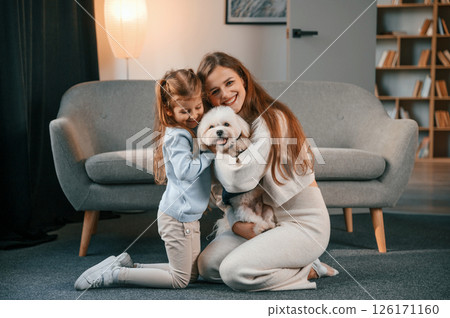 On the floor with pet together. Mother with daughter is at home with maltese dog 126171160