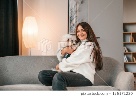 Sitting on the sofa. Beautiful woman is with maltese dog is at home Sitting on the sofa. Beautiful woman is with maltese dog is at home 126171220